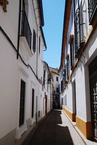 Narrow street between buildings against sky