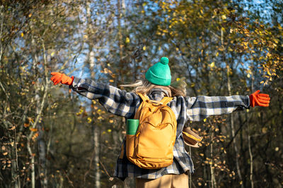 Rear view of man standing by tree trunk