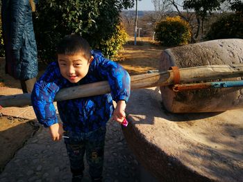 Portrait of boy leaning on wood
