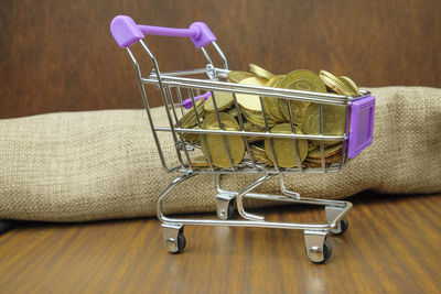 Close-up of coins in shopping cart on wooden table