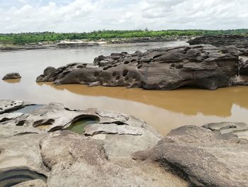 Scenic view of rocks on shore against sky