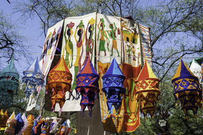 Low angle view of lanterns hanging by trees against sky
