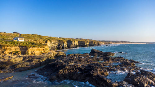 Scenic view of sea and cliffs against clear blue sky