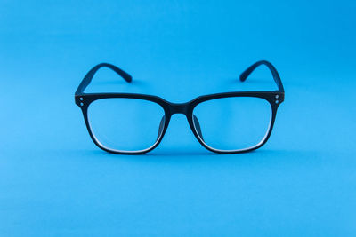Close-up of eyeglasses against blue background