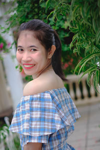 Portrait of smiling young woman by plants