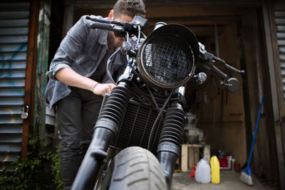 Mechanic fixing motorcycle outside workshop