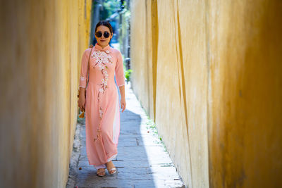 Full length of woman walking amidst walls at alley
