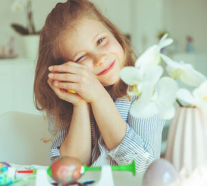 Portrait of cute girl holding easter egg while sitting at home