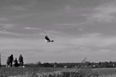 People and seagull against sky