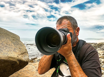 Portrait of man photographing against sky