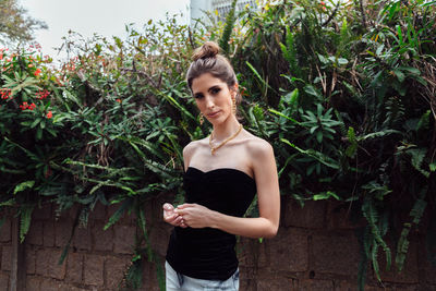 Young woman standing against plants