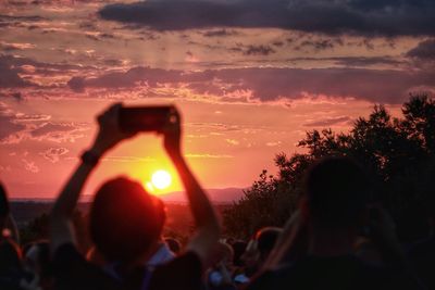 People photographing in city against sky during sunset