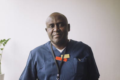 Portrait of confident male doctor against wall at hospital