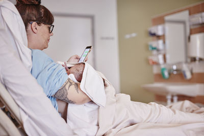 Mother with newborn baby in hospital using phone