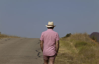 Side view of man standing on field against clear sky