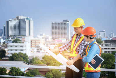 Engineers discussing while standing against buildings in city