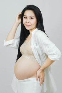 Portrait of young woman standing against white background