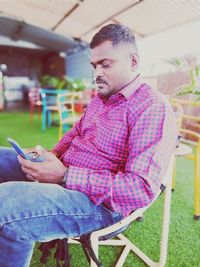 Young man using mobile phone while sitting on chair