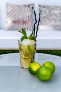 A image of a freshly made mojito cocktail on a table with lime garnish