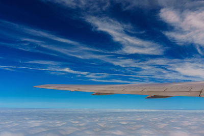 Airplane wing over clouds against sky