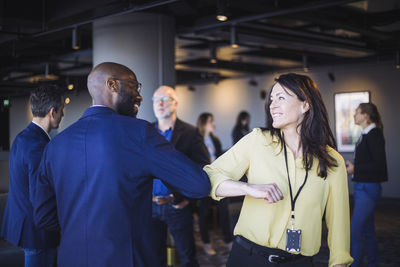 Rear view of male entrepreneur greeting colleague with elbow in office