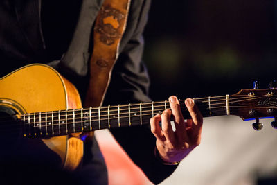 Midsection of man playing guitar