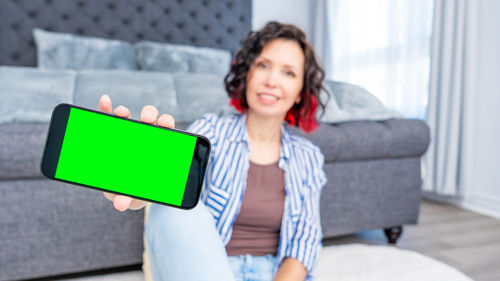 Young woman using digital tablet while sitting on sofa at home