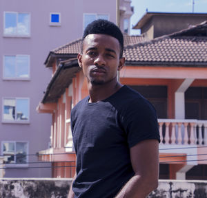 Portrait of young man standing against building