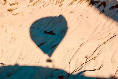 Shadow of hot air balloon on sand during sunny day