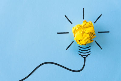 High angle view of yellow light bulb against blue sky