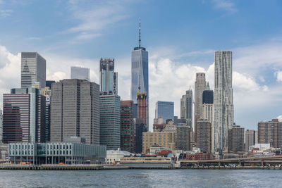 City at waterfront against cloudy sky