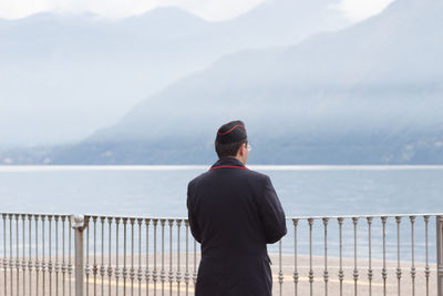 Rear view of man looking at mountains against sky