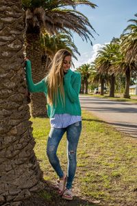 Full length of young woman standing on palm tree