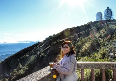 Young woman using smart phone against mountains