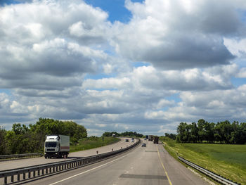 Truck moving on highway against cloudy sky