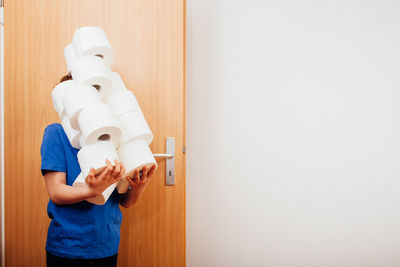 Full length of boy holding white dress standing against wall at home