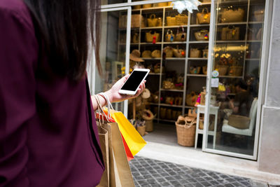 Rear view of woman using mobile phone at store