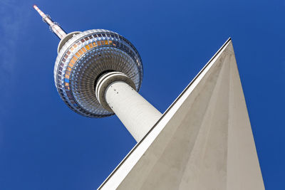 Low angle view of fernsehturm by triangle shape against blue sky