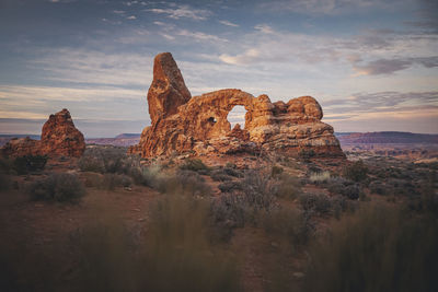 Rock formations on landscape against cloudy sky