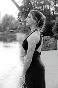 Rear view of young woman standing against trees