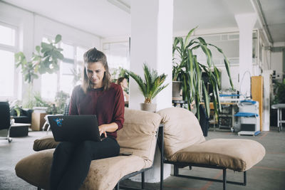 Young woman using phone while sitting on chair