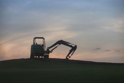Traditional windmill on field against sky during sunset