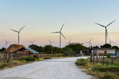 Wind turbines on field against sky during sunset