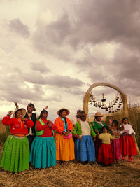 Rear view of friends against cloudy sky