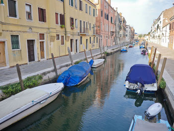 Boats moored in canal amidst buildings in city