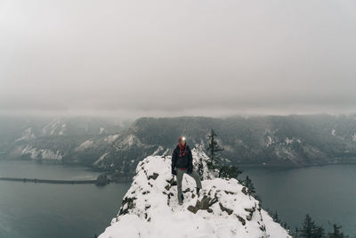 Rear view of woman looking at mountain against sky during winter