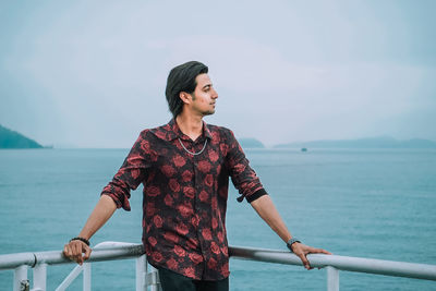 Young man looking at sea against sky