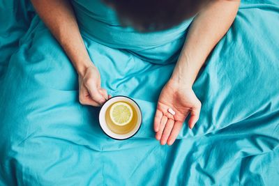 Midsection of mid adult man having medicine while sitting on bed at home