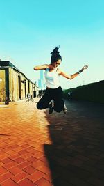 Young woman jumping on footpath
