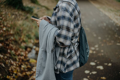 Midsection of man holding camera while standing on land